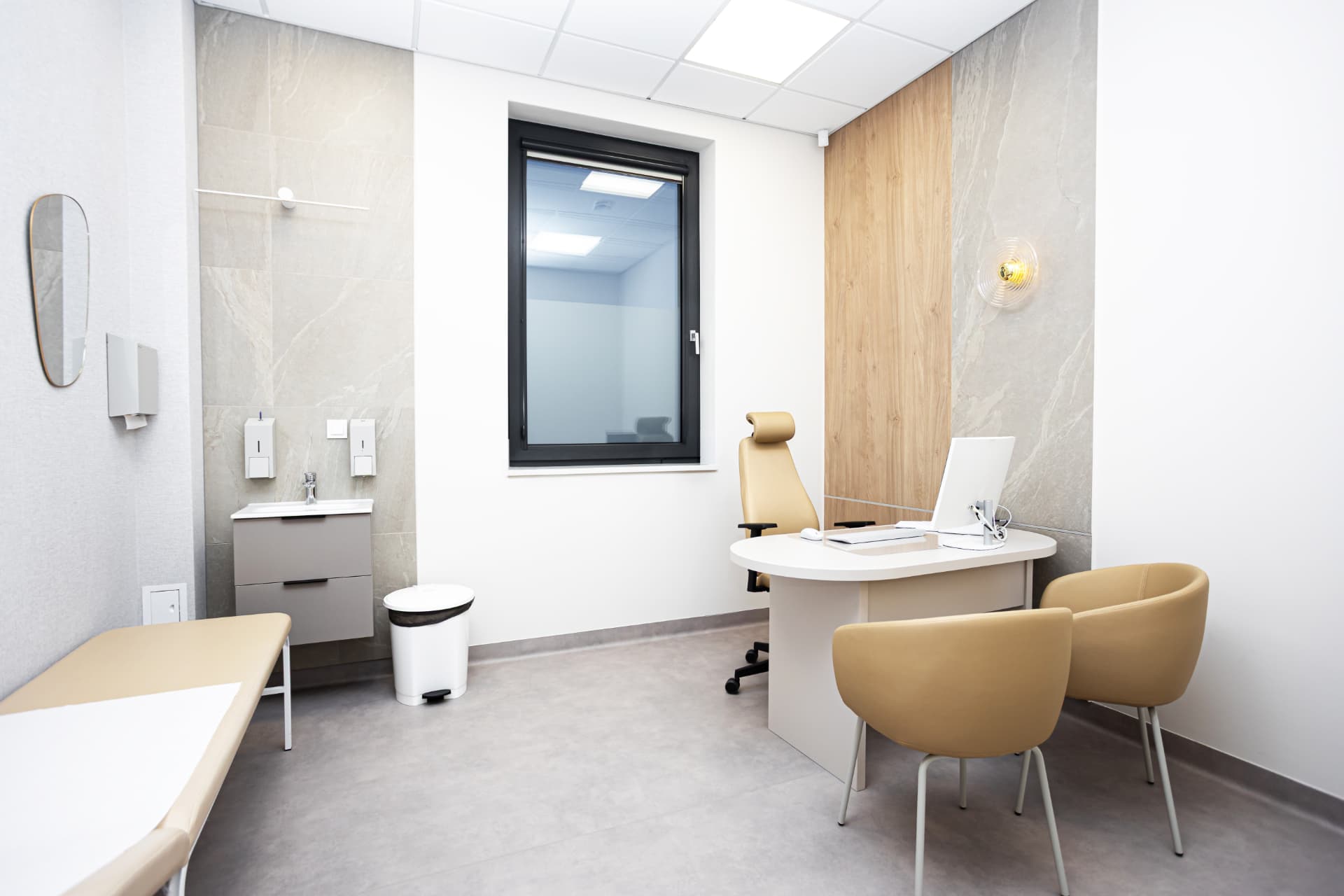 Salle d'examen clinique aux surfaces lavables, lavabo et distributeurs muraux