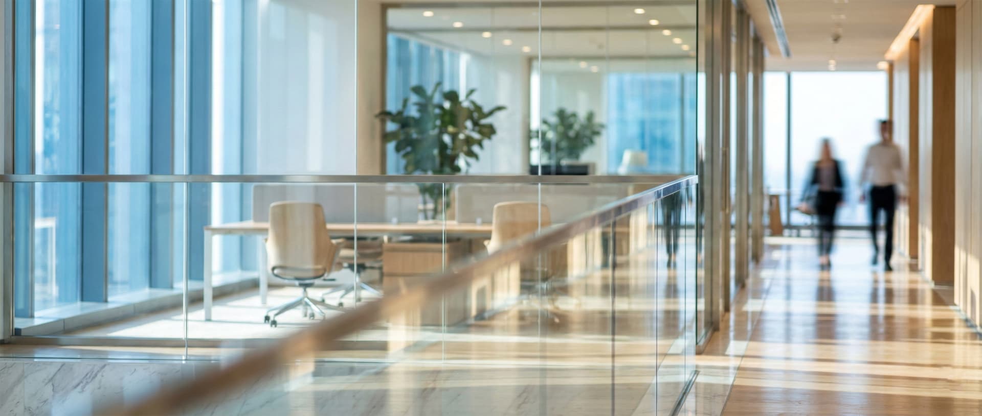 Corridor vitré d'un immeuble de bureaux, planchers polis et postes de travail en arrière-plan